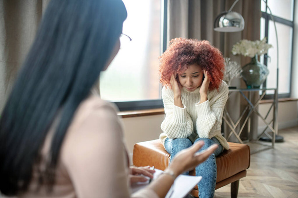 Woman having headache while speaking with psychologist - Fotoğraf, Görsel