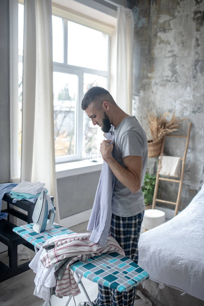 Bearded man wearing pajamas feeling busy with ironing - Φωτογραφία, εικόνα