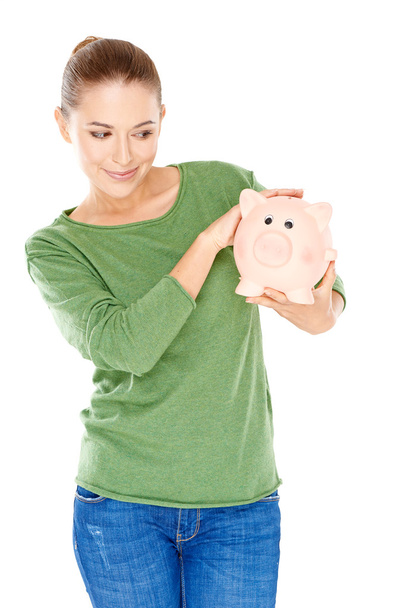 Woman giving her piggy bank a speculative look - Фото, изображение