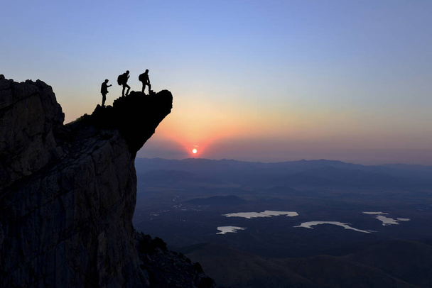 drie vrienden kijken naar de zonsopgang in de bergen van de berg - Foto, afbeelding
