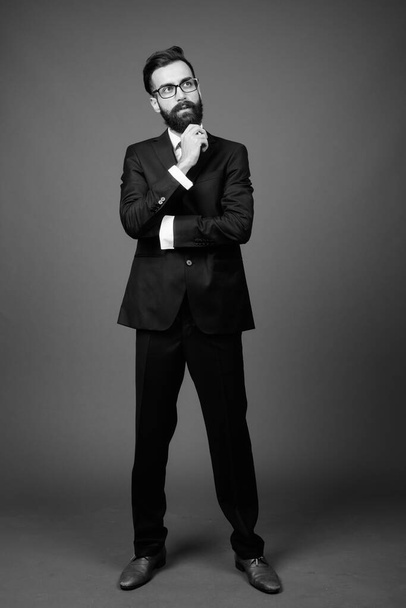 Giovane bell'uomo d'affari persiano barbuto contro sfondo grigio - Foto, immagini