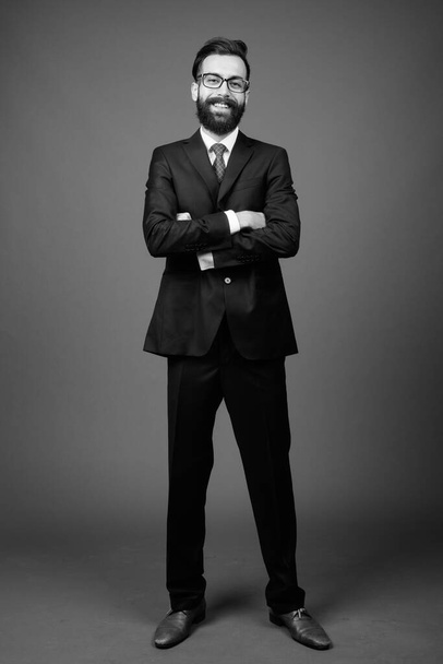 Giovane bell'uomo d'affari persiano barbuto contro sfondo grigio - Foto, immagini