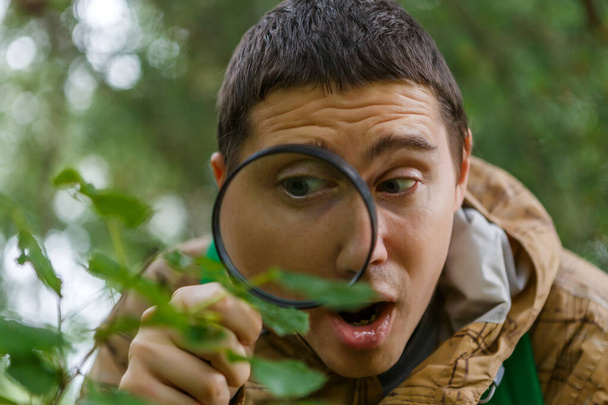 Foto eines jungen Botanikers mit Lupe im Wald an einem Sommertag - Foto, Bild