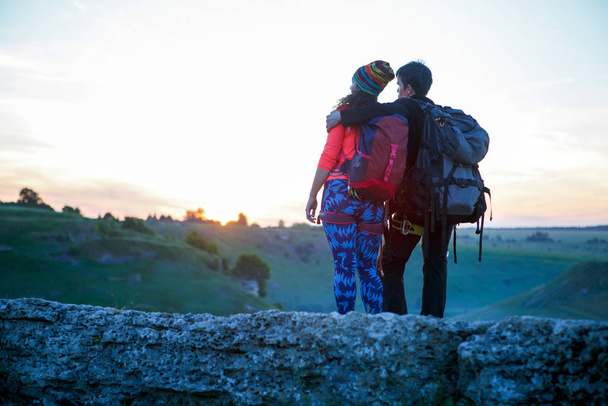 Foto von hinten von umarmenden jungen Touristen auf dem Hügel bei Sonnenuntergang - Foto, Bild