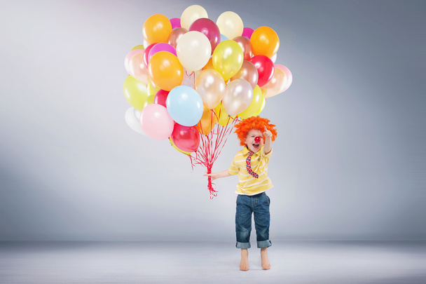 Small jumping boy holding bunch of balloons - Фото, зображення