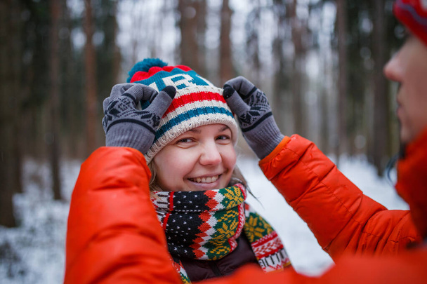 午後の冬の森の中で女性の帽子を調整する男の写真 - 写真・画像