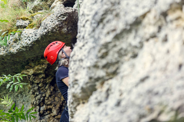 Zdjęcie turystki w czerwonym kasku wspinającej się na skałę w ciągu dnia - Zdjęcie, obraz