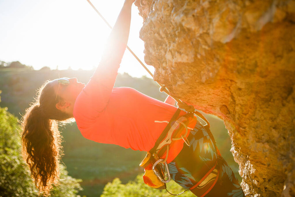 Kıvırcık saçlı kadın turistin yaz günü kaya üzerinde tırmandığı fotoğraf. - Fotoğraf, Görsel