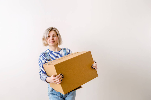 Photo of young woman with cardboard box in new empty apartment - Zdjęcie, obraz