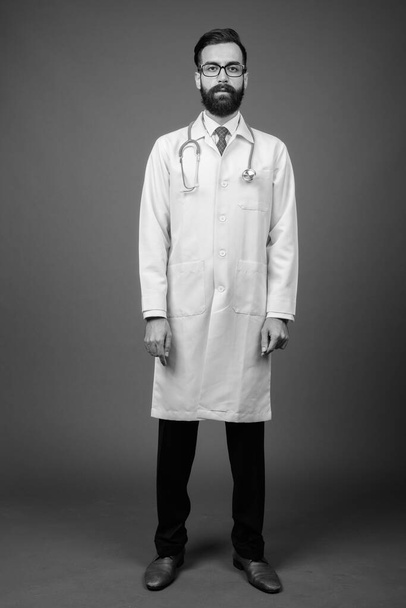Joven guapo barbudo médico hombre persa contra fondo gris - Foto, Imagen