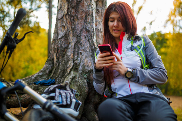 Image de fille avec téléphone cellulaire dans la forêt d'automne l'après-midi
 - Photo, image