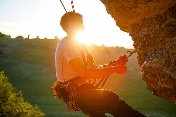 Φωτογραφία ενός άντρα να σκαρφαλώνει πάνω από την πέτρα. Φαινόμενο ηλιακού φωτός - Φωτογραφία, εικόνα