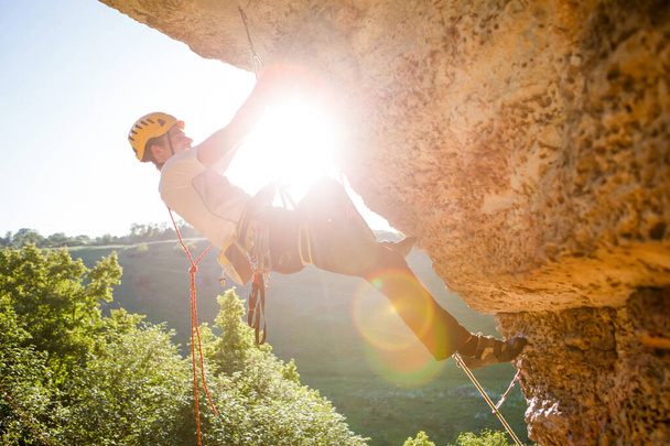 Изображение человека-альпиниста в шлеме, карабкающегося по скале. Эффект солнечной вспышки
. - Фото, изображение