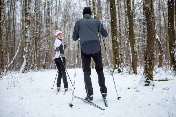 Зображення спортивної жінки та чоловіка, що катається на лижах у зимовому лісі протягом дня
 - Фото, зображення