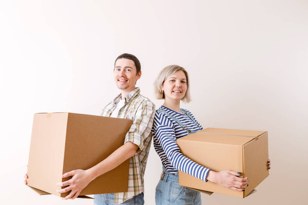 Foto de joven hombre y mujer con caja de cartón en nuevo apartamento vacío
 - Foto, Imagen