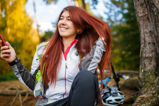 Foto de mujer feliz con teléfono inteligente en el bosque de otoño por la tarde
 - Foto, Imagen