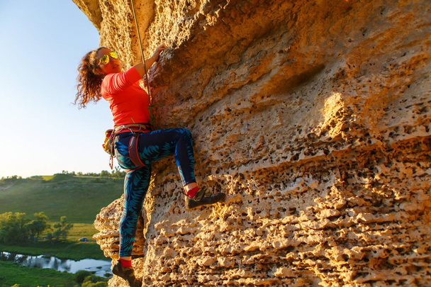 Pcture göndör hajú hegymászó lány mászó szikla a nyári napon - Fotó, kép