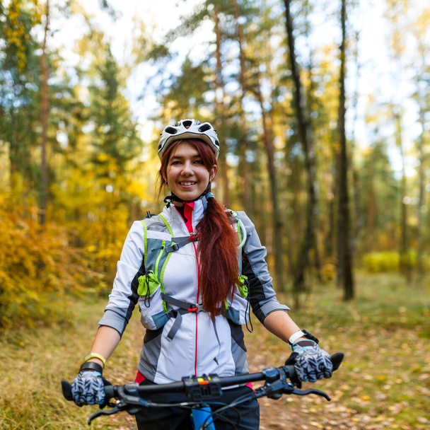 Obraz dziewczyny w kasku jeżdżącej na rowerze przez jesienny las - Zdjęcie, obraz