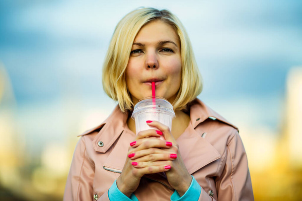 Портрет блондинки, пьющей молочный коктейль в парке, размытый фон
 - Фото, изображение