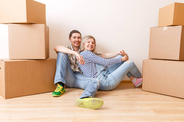 Foto de una joven pareja sentada en el suelo entre cajas de cartón en un apartamento nuevo
 - Foto, imagen