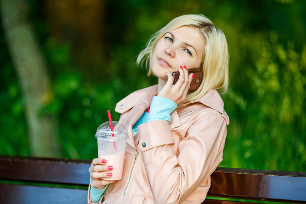 Tyttö pirtelö puhuu puhelimessa istuu penkillä kadulla kesällä
 - Valokuva, kuva
