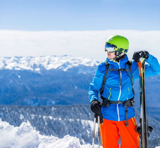 Fotografie sportovního muže s lyžemi v pozadí horské krajiny - Fotografie, Obrázek