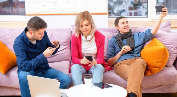 Друзі сидять на дивані, спілкуються і використовують смартфон, настільний комп'ютер, ноутбук. Концепція соціальних медіа
. - Фото, зображення