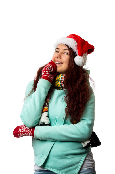 Foto von Brünette in Weihnachtsmütze, die nach oben schaut auf leerem weißem Hintergrund - Foto, Bild