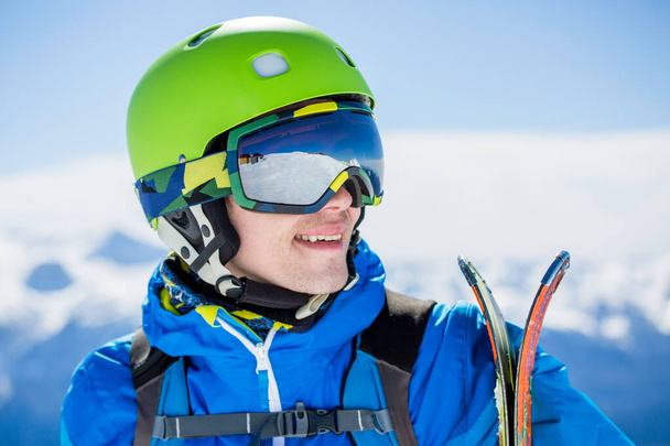 Портрет спортивного человека с лыжами на фоне горного пейзажа - Фото, изображение