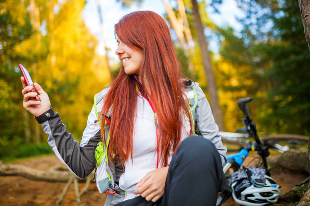 Photo de femme heureuse avec téléphone portable dans la forêt d'automne l'après-midi
 - Photo, image