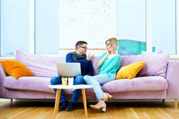 Мужчина и женщина сидят на диване, общаются и пользуются настольным компьютером. Концепция социальных сетей
. - Фото, изображение