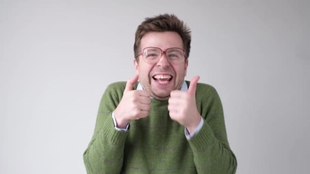 Щасливий чоловік в зеленому светрі з великими пальцями вгору жестом
 - Кадри, відео