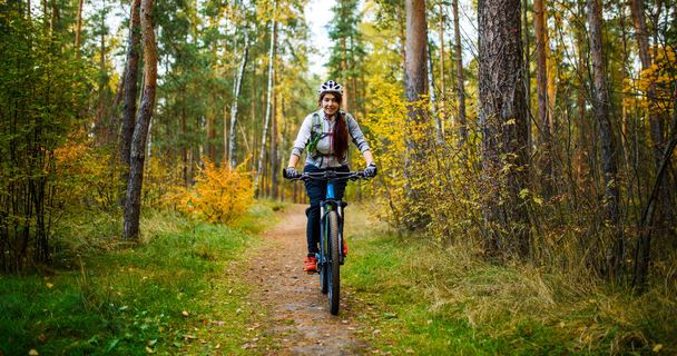 Photo de fille en casque chevauchant à vélo dans la forêt d'automne
 - Photo, image