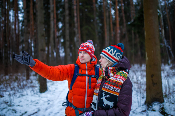 Kép a nő és a férfi mutatja kezét előre a téli erdőben a nap folyamán - Fotó, kép