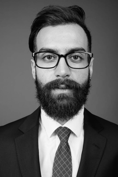 Young handsome bearded Persian businessman against gray background - Foto, immagini