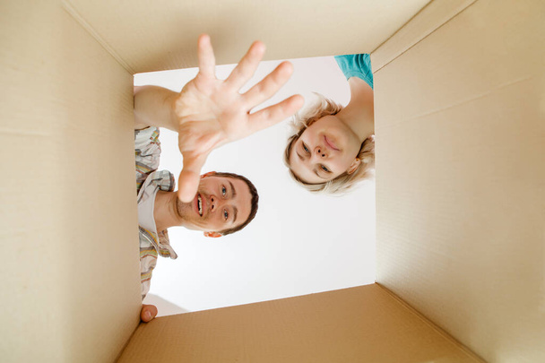 Изображение мужчины и женщины, заглядывающих в открытую картонную коробку
 - Фото, изображение