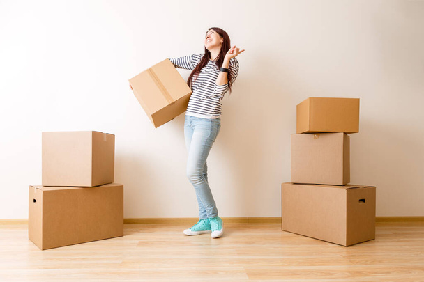 Image of young woman among cardboard boxes in new apartment - Foto, Imagen