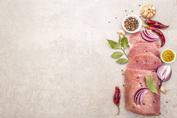 Raw pork tenderloin with vegetables and spices. Cooking meat background, fresh brisket boneless steak on stone background, top view, copy space. - Photo, Image