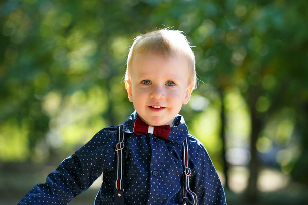 Πορτρέτο ενός χαριτωμένου μικρού αγοριού στο φόντο της φύσης. Περπάτα στο πάρκο. Οικογενειακή ζωή. - Φωτογραφία, εικόνα