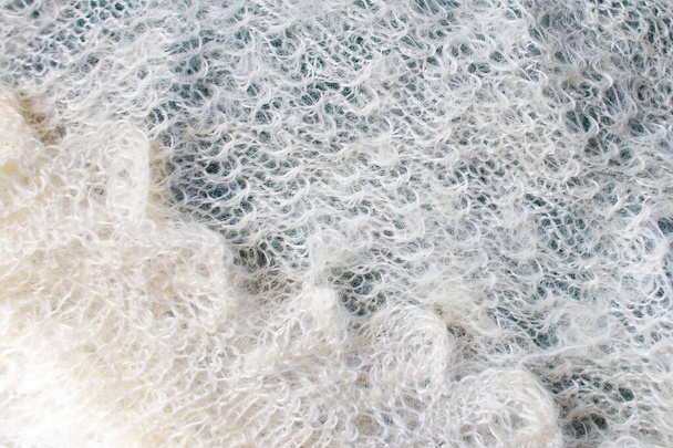 La texture d'une écharpe chaude en laine blanche tricotée. Arrière-plan de châle duveteux Orenburg
 - Photo, image