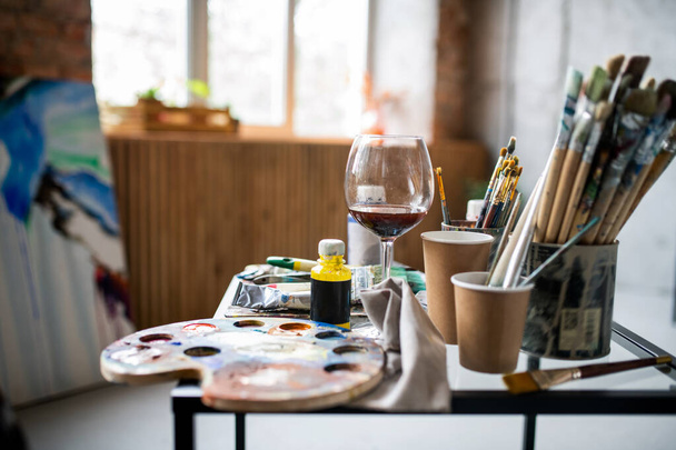 Local de trabalho do pintor profissional contemporâneo com paleta, vários pincéis e outros equipamentos na mesa
 - Foto, Imagem