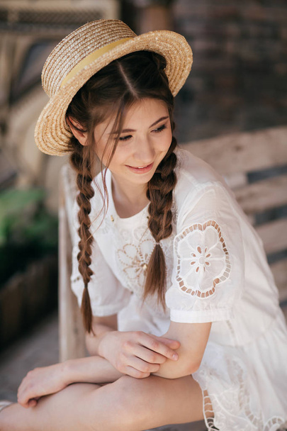 beautiful young woman with two braids and straw hat outdoor - Fotó, kép
