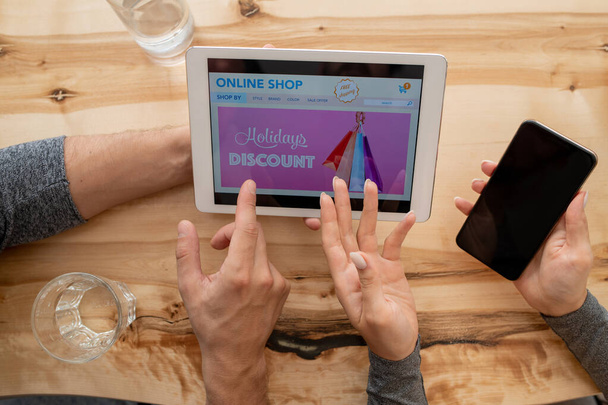 Вид сверху человеческих рук во время обсуждения домашней страницы интернет-магазина в сенсорной панели, когда вы собираетесь сделать заказ
 - Фото, изображение