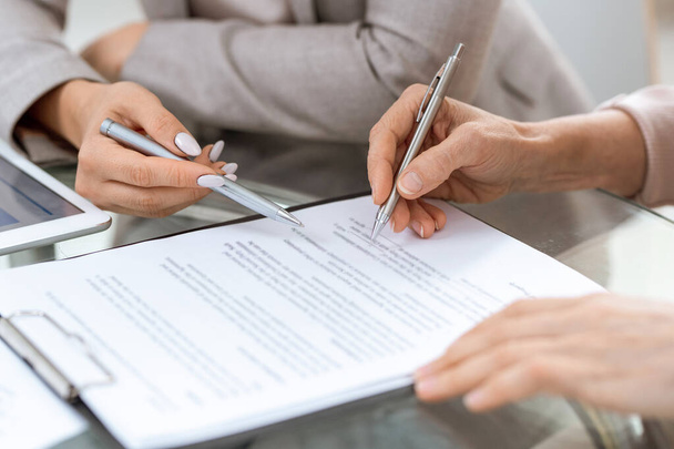 Людські руки з ручками над фінансовим документом в момент підписання підпису після обговорення його пунктів
 - Фото, зображення