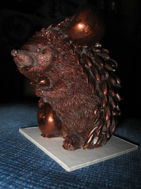 Çikolatalı kirpi heykelciği çikolata elması taşıyor. - Fotoğraf, Görsel