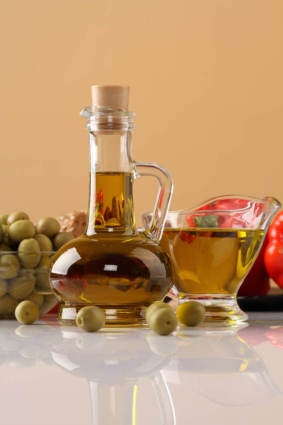 Olive oil, olives and peppers on beige background - Photo, image