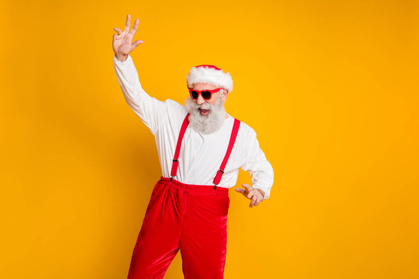 Portrait of positive funny santa claus hipster in red hat enjoy christmas party event fun newyear celebration dance club wear shirt suspenders isolated over yellow color background - Photo, Image