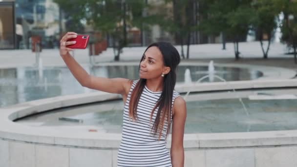 Menina africana alegre tomando selfie na frente de fontes
 - Filmagem, Vídeo