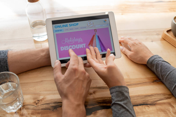 Mãos de jovem casal apontando para loja on-line home page na tela touchpad enquanto vai fazer a ordem
 - Foto, Imagem