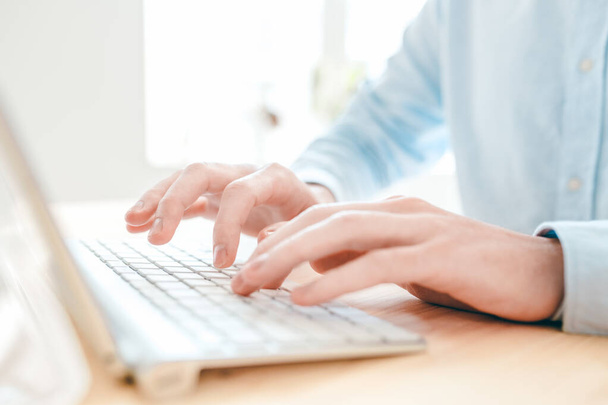 Mains de jeune analyste ou designer tapant sur un petit clavier blanc assis à table devant l'ordinateur
 - Photo, image